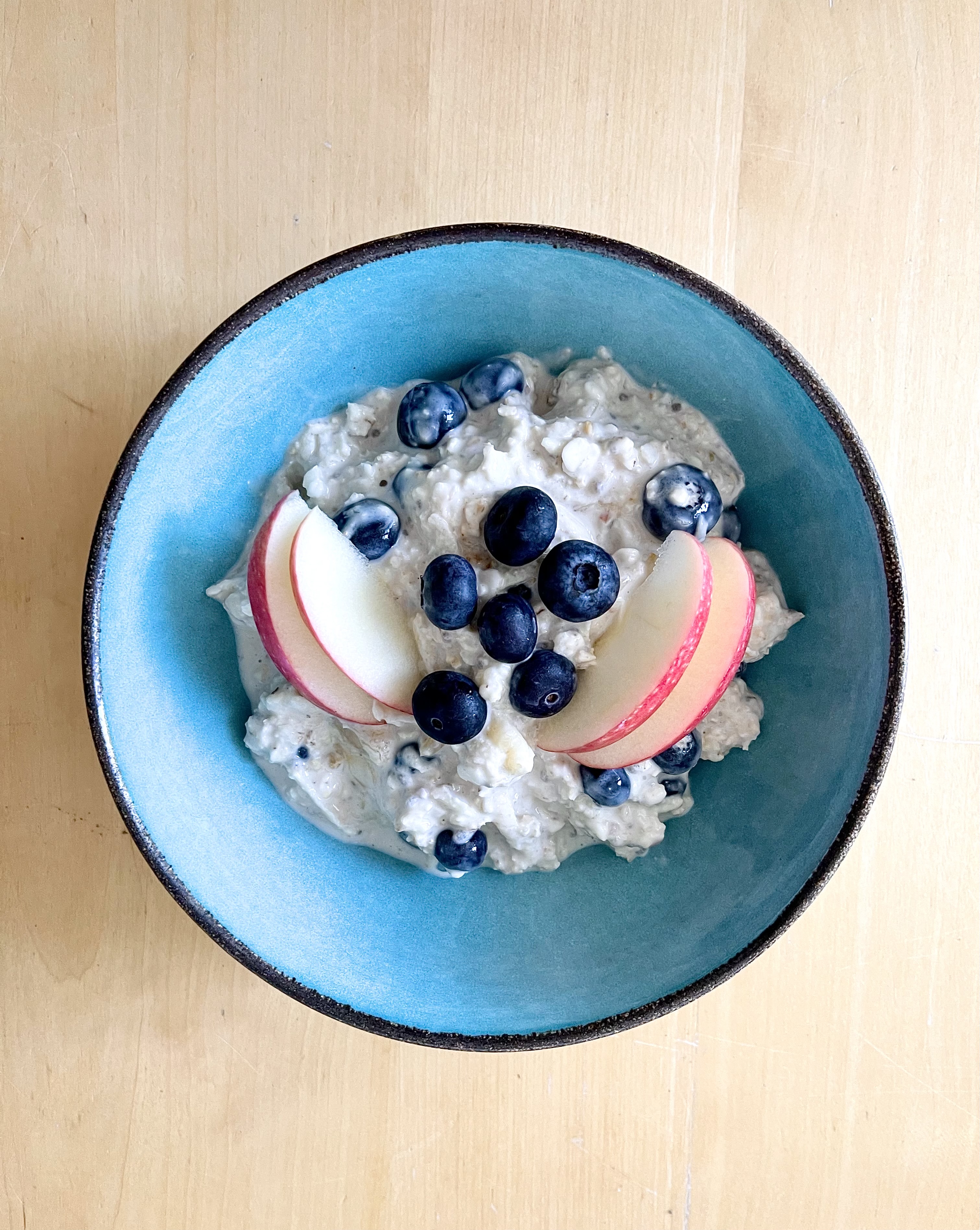 Joghurt-Müsli gemixt aus Gerstoni Gerstenflocken, garniert mit Blaubeeren und Apfelscheiben in blauer Schale