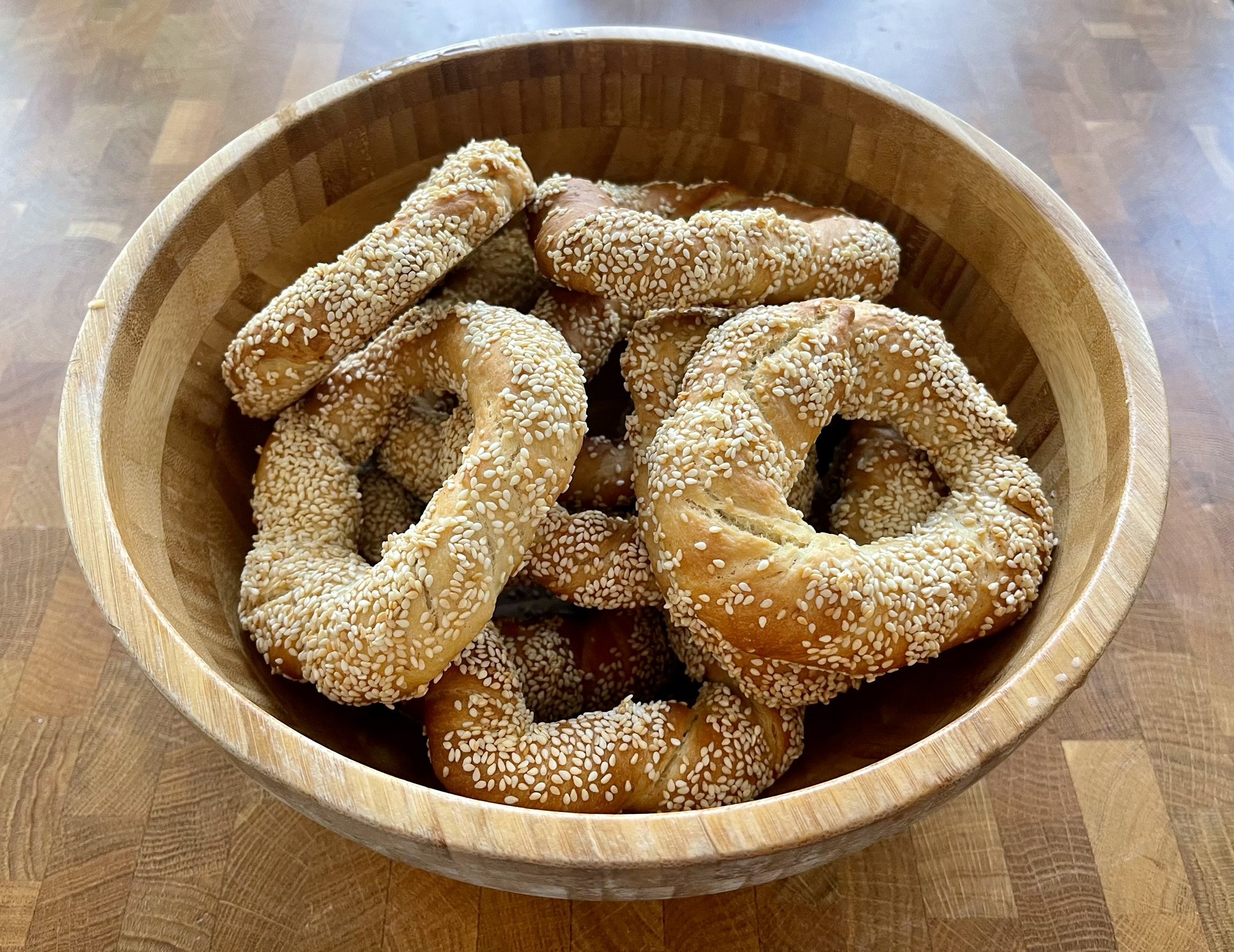 Mehrere Sesamkringel (Simit) in einer Holzschüssel auf einem Holztisch.