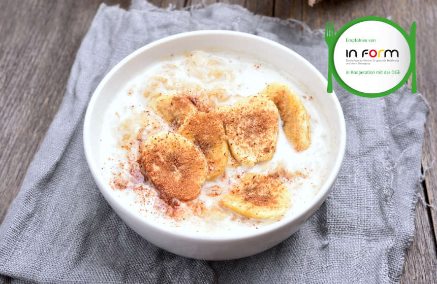 Porridge mit Gerstenflocken garniert mit Bananenscheiben und Zimt in weißer Schale. Oben rechts das Inform Logo.