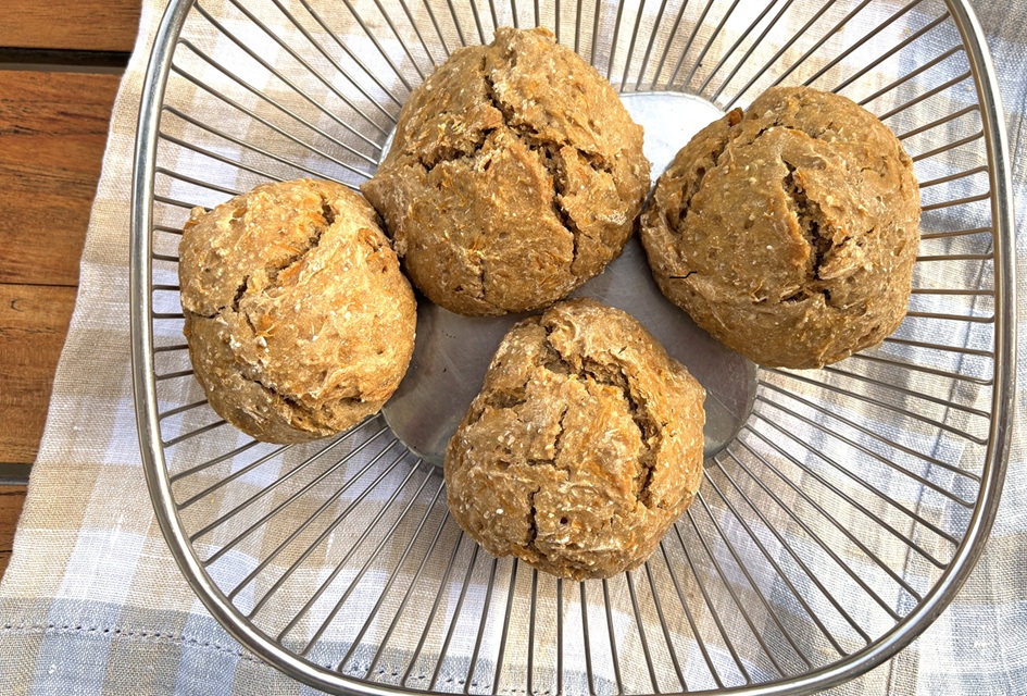 Vier Gerstenbrötchen in einem Metallkorb auf einer beige-blau karierten Decke