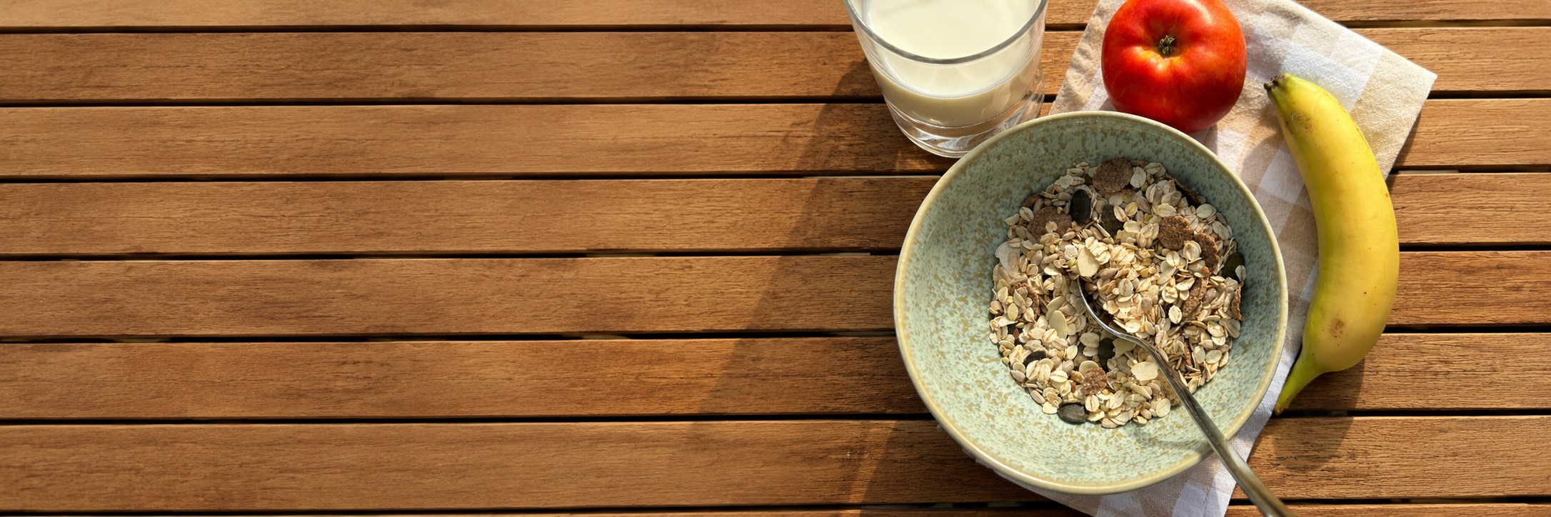 Leckeres Gerstenmüsl mit einem Glas Milch, als auch ein Apfel und eine Banane auf einem Tisch
