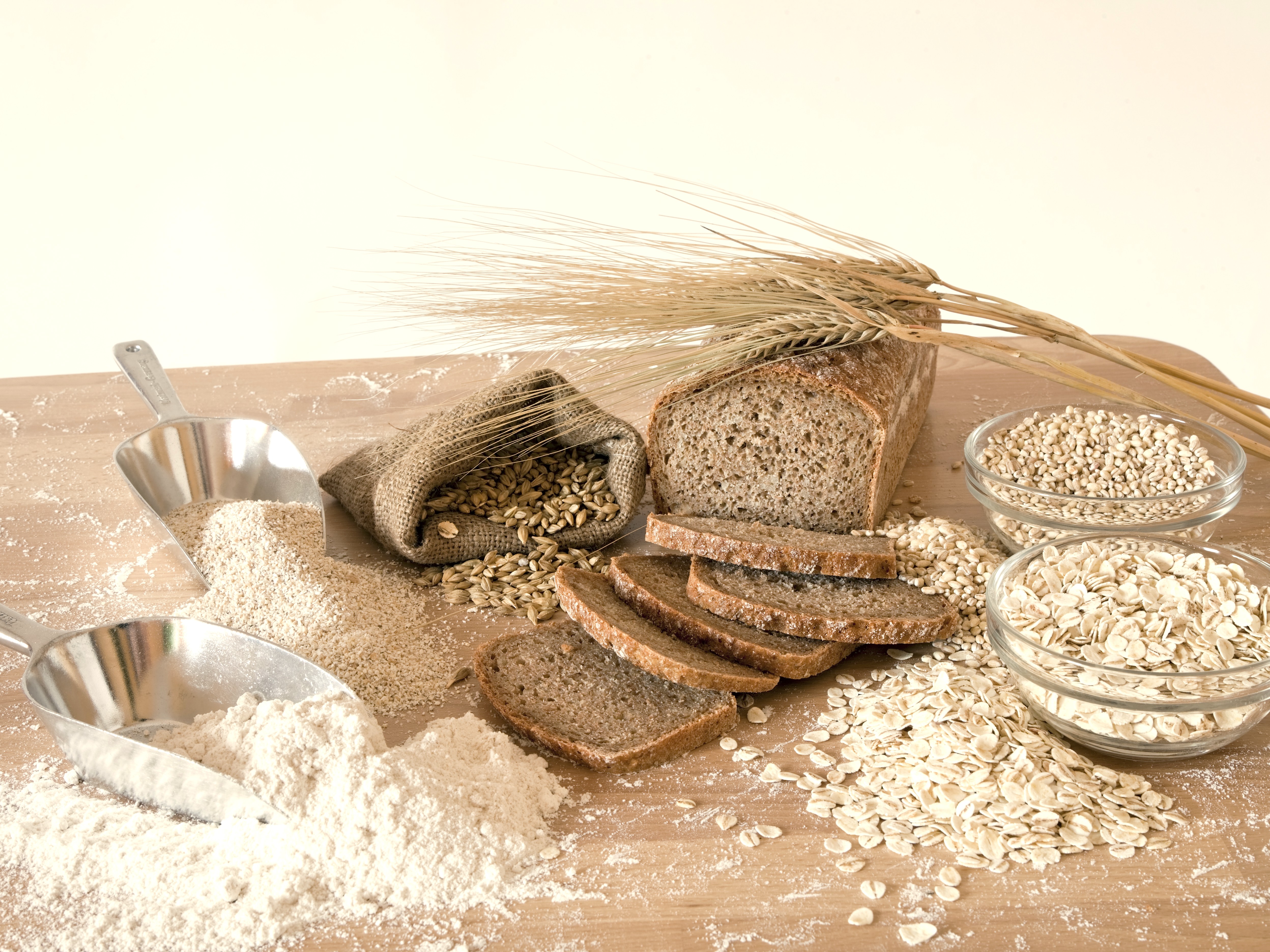Gerstenflocken, Gerstenmehl, Gerstenähren mit Broten auf einem Holzbrett